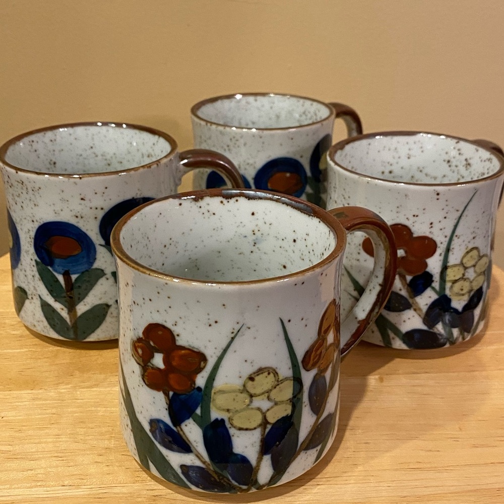 Four glazed, speckled stoneware mugs.